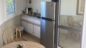 Una cocina compacta con un refrigerador de acero inoxidable, un lavamanos y una zona de comedor con una mesa redonda y sillas.
