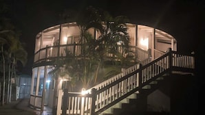 Ein rundes Gebäude mit einer Wendeltreppe, die zum Eingang führt, umgeben von Palmen.
