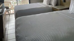 A hotel room with two beds, a desk, a chair, a balcony with a view, and an air conditioning unit. - Queen Deluxe Double at Boundless Bliss Hotel (Southside)