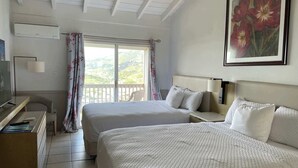 A hotel room with two beds, a desk with a TV, a chair, a window with curtains, and a painting on the wall. - Queen Deluxe Double at Boundless Bliss Hotel (Southside)