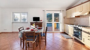A kitchen with a dining table, chairs, a TV, and a view of the outdoors. - ‘Acacia’ Apartment with Sea View, Wi-Fi and Air Conditioning (Ceriale)