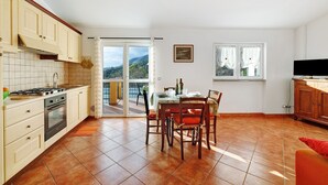 A kitchen with a dining area, a TV, and a view of the outdoors. - 'Carrubo' Apartment with Sea View, Wi-Fi and Air Conditioning (Ceriale)