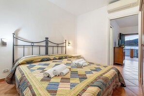 A bedroom with a bed, a nightstand, a wall-mounted light, and a view of the outside. - Apartment 'Ginestra' with Mountain View, Wi-Fi and Air Conditioning (Ceriale)