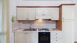 A kitchen with white cabinets, a gas stove, a sink, and a tiled backsplash. - Apartment 'Ginestra' with Mountain View, Wi-Fi and Air Conditioning (Ceriale)