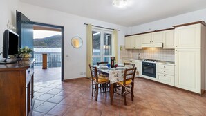 A kitchen with a dining table, chairs, cabinets, and a view through a window. - Apartment 'Ginestra' with Mountain View, Wi-Fi and Air Conditioning (Ceriale)