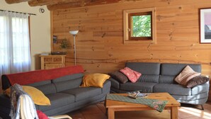 A cozy living room with a grey sofa, a wooden coffee table, and a window with a view of greenery. - Mountain chalet with central fireplace 10 min from Saint-Lary and 30 from Piau (Aragnouet)
