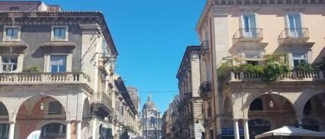 A street with historic buildings, pedestrians, and a clear blue sky.