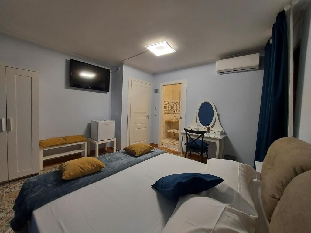 Una camera d'albergo con un letto, una scrivania con uno specchio, una televisione e un armadio.