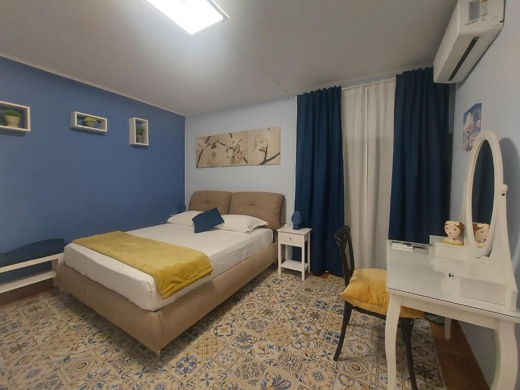 Ein Schlafzimmer mit Bett, Nachttisch, Stuhl, Kommode und Spiegel.