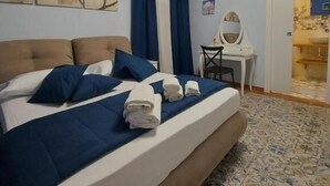 A hotel room with a large bed, a desk, and a bathroom visible through an open door. - B&B Piazza Mazzini (Catania)