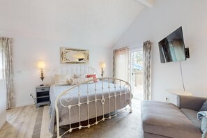 Een slaapkamer met een bed, nachtkastjes, een televisie en een bank.