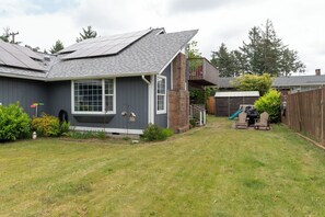 A residential house with a sloped roof, a front porch, and a backyard with a slide. - Quiet 3BR Retreat, EV Charger, Fenced Yard (Tide) (Westport)