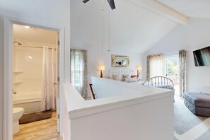 A bedroom with a bed, a bedside table, a mirror, and a window. - Quiet 3BR Retreat, EV Charger, Fenced Yard (Tide) (Westport)