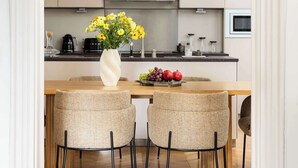 Une cuisine moderne avec un coin repas, comprenant une table en bois, des chaises en osier et un luminaire suspendu.