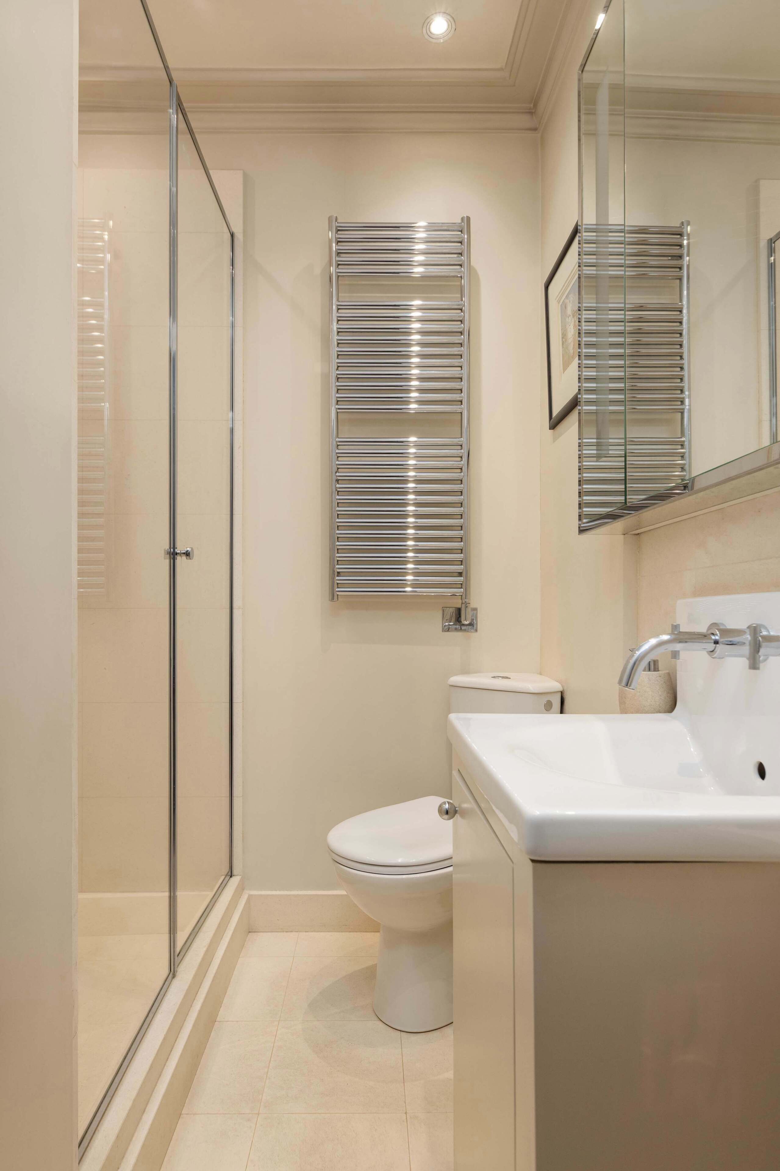 A modern bathroom with a glass shower enclosure, a toilet, and a sink with a mirror above.