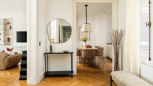 Un salon moderne comprenant un canapé, une console, un miroir, un coin repas avec des chaises et un banc.