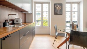 Una cocina moderna con encimera de madera, electrodomésticos de acero inoxidable y un amplio ventanal con vistas al balcón.