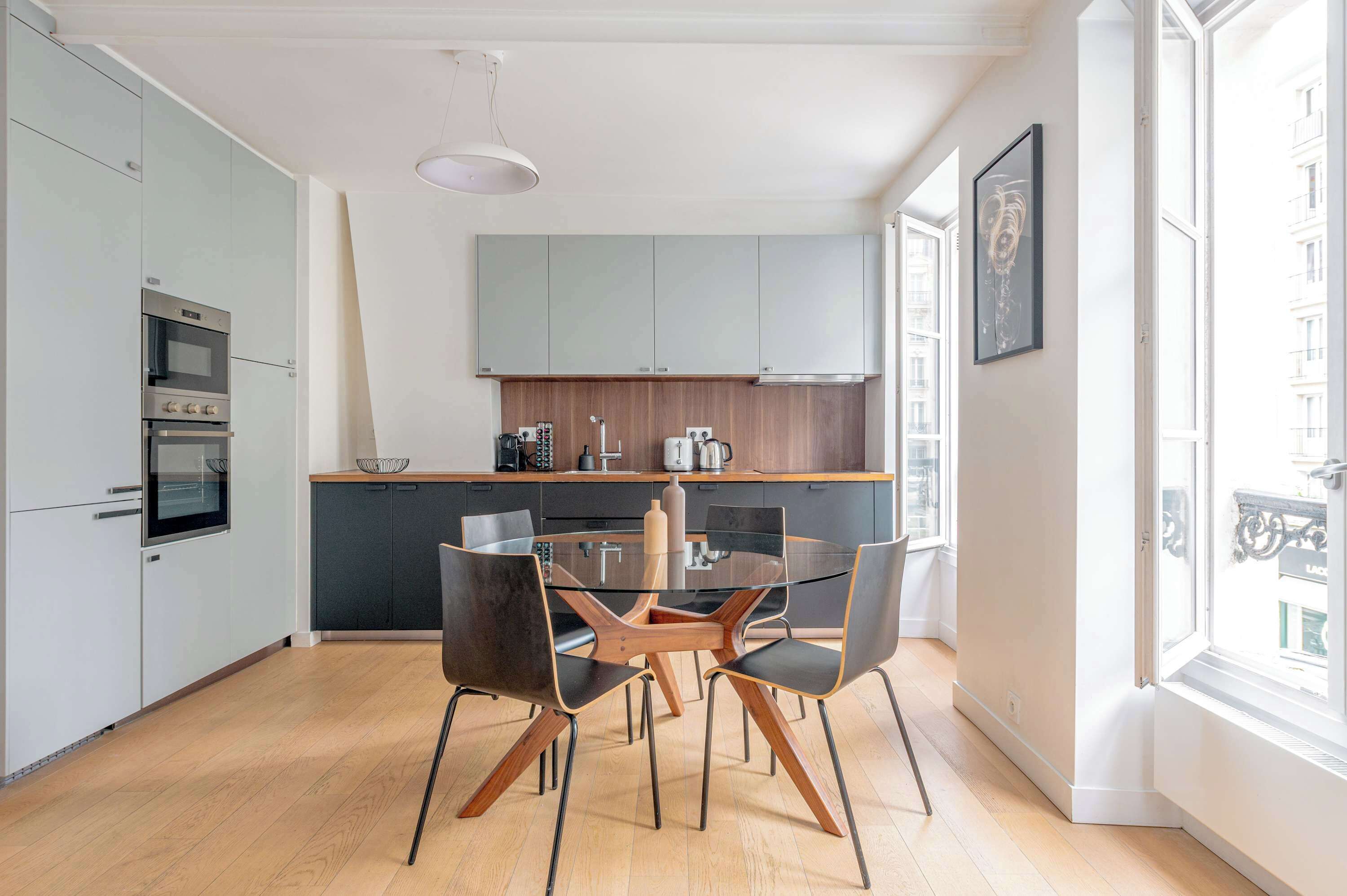 A modern kitchen with a central island, built-in appliances, and a large window providing natural light.