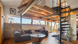 A modern living room with a wooden ceiling, a spiral staircase, a gray sofa, and a round coffee table. - Apartment 'I'd Love To Be Home' with Shared Pool, Shared Terrace and Wi-Fi (Bidingen)