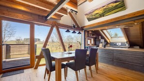 A dining area with a wooden table and chairs, large windows, and a view of the outdoors. - Apartment 'I'd Love To Be Home' with Shared Pool, Shared Terrace and Wi-Fi (Bidingen)