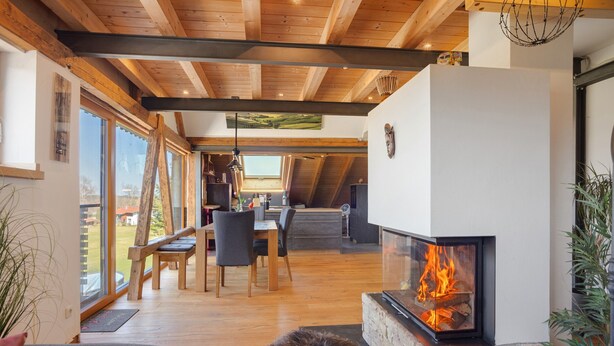 A modern interior with a fireplace, wooden beams, and a dining area with chairs and a table. - Apartment 'I'd Love To Be Home' with Shared Pool, Shared Terrace and Wi-Fi (Bidingen)