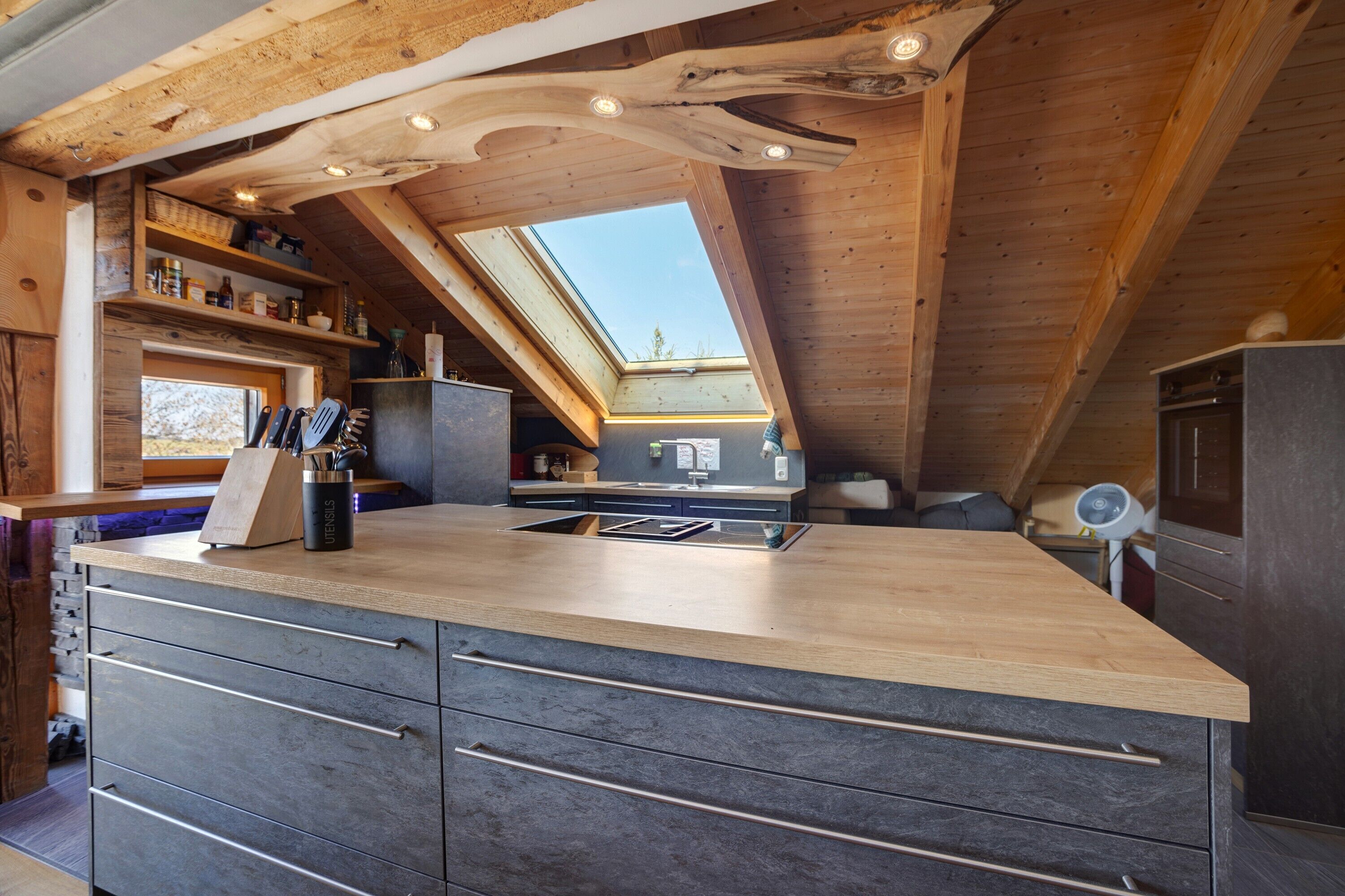 A kitchen with a wooden ceiling, skylight, and built-in drawers.