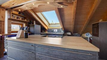 A kitchen with a wooden ceiling, skylight, and built-in drawers.