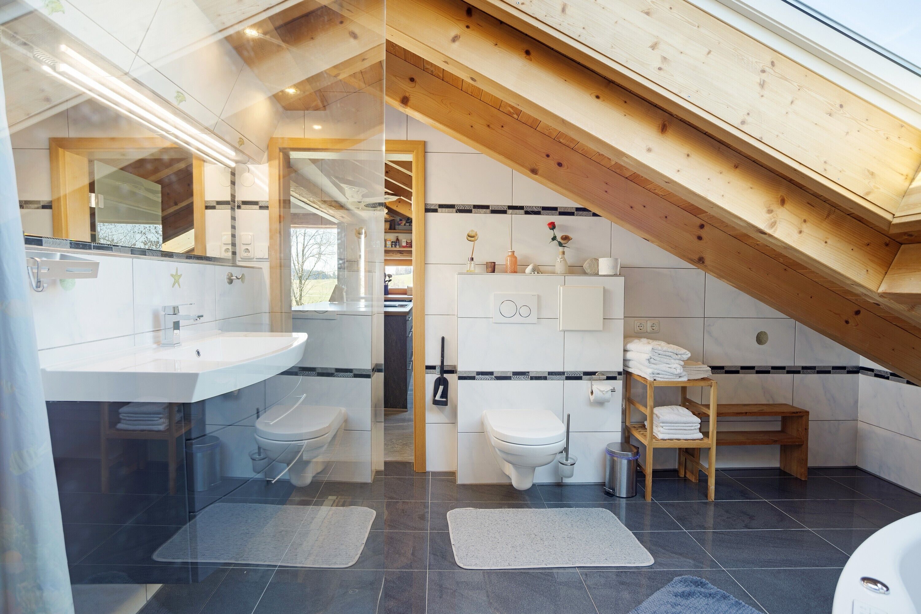 A modern bathroom with a skylight, a wooden ceiling, and a white vanity.