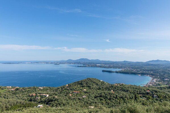 A coastal landscape with a view of the sea, hills, and scattered buildings. - Villa Oliveta in Spartilas (Corfu)