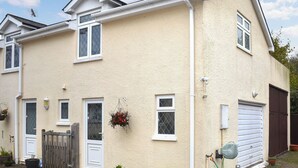 Ein zweigeschossiges Haus mit weißer Fassade, einer Haustür und einer Garage.