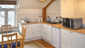 Eine kleine Küche mit weißen Schränken, einer Holz Arbeitsplatte und einer eingebauten Mikrowelle.