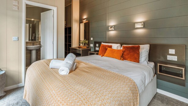Een moderne hotelkamer met een groot bed, een nachtkastje, een spiegel en een badkamer zichtbaar door een open deur.