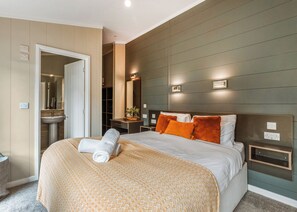 Een moderne hotelkamer met een groot bed, een nachtkastje, een spiegel en een badkamer zichtbaar door een open deur.