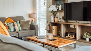 Een moderne woonkamer met een bank, salontafel, televisie en open haard.