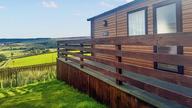Una cabana de fusta amb un balcó que s'obre a un paisatge verd.