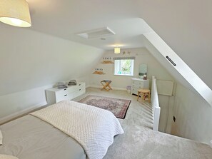 Quarto com cama, cômoda, penteadeira, janela e radiador.