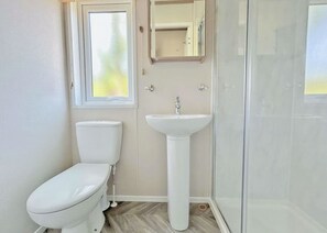 Ein Badezimmer mit Toilette, Waschbecken und Duschkabine aus Glas.