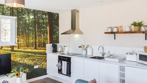 A modern kitchen with white cabinetry, a built-in oven, and a coffee maker. - 1 bedroom accommodation in Lydney, Forest of dean (Lydney, Forest of dean)