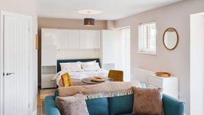 A bedroom with a bed, a sofa, a dining table, and a small kitchen area. - 1 bedroom accommodation in Lydney, Forest of dean (Lydney, Forest of dean)