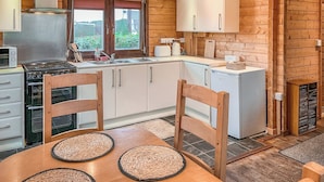Una cocina con armarios de madera, estufa, refrigerador y una mesa de comedor con sillas.