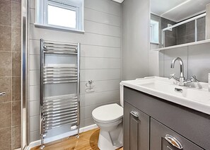 Un baño con ducha, inodoro, lavamanos y espejo.