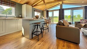 Een ruime keuken met een centraal eiland, een eethoek met stoelen en een groot raam met uitzicht op de omgeving.