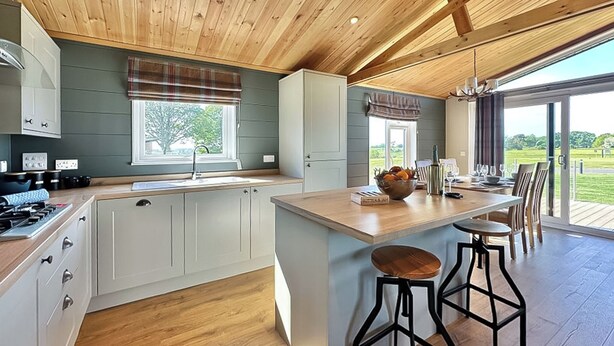 Een moderne keuken met een centraal eiland, barstoelen en uitzicht op de omgeving.