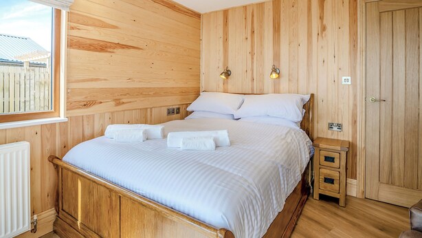 A wooden-paneled bedroom with a bed, bedside tables, and a window. - 1 bedroom accommodation in Ripponden (Ripponden)