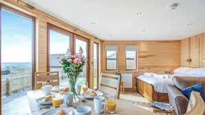 A room with a dining table set for breakfast, a bed, and large windows offering a view. - 1 bedroom accommodation in Ripponden (Ripponden)