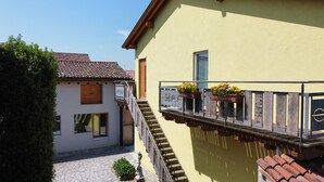 A building with a yellow exterior, a wooden staircase, and flower boxes on the balcony. - Charming apartment with private parking near the Cremona Racing Circuit (Casteldidone)