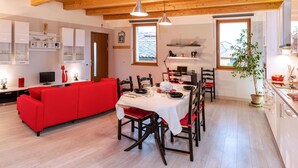 A modern kitchen with a dining area, wooden flooring, and a red sofa. - Charming apartment with private parking near the Cremona Racing Circuit (Casteldidone)