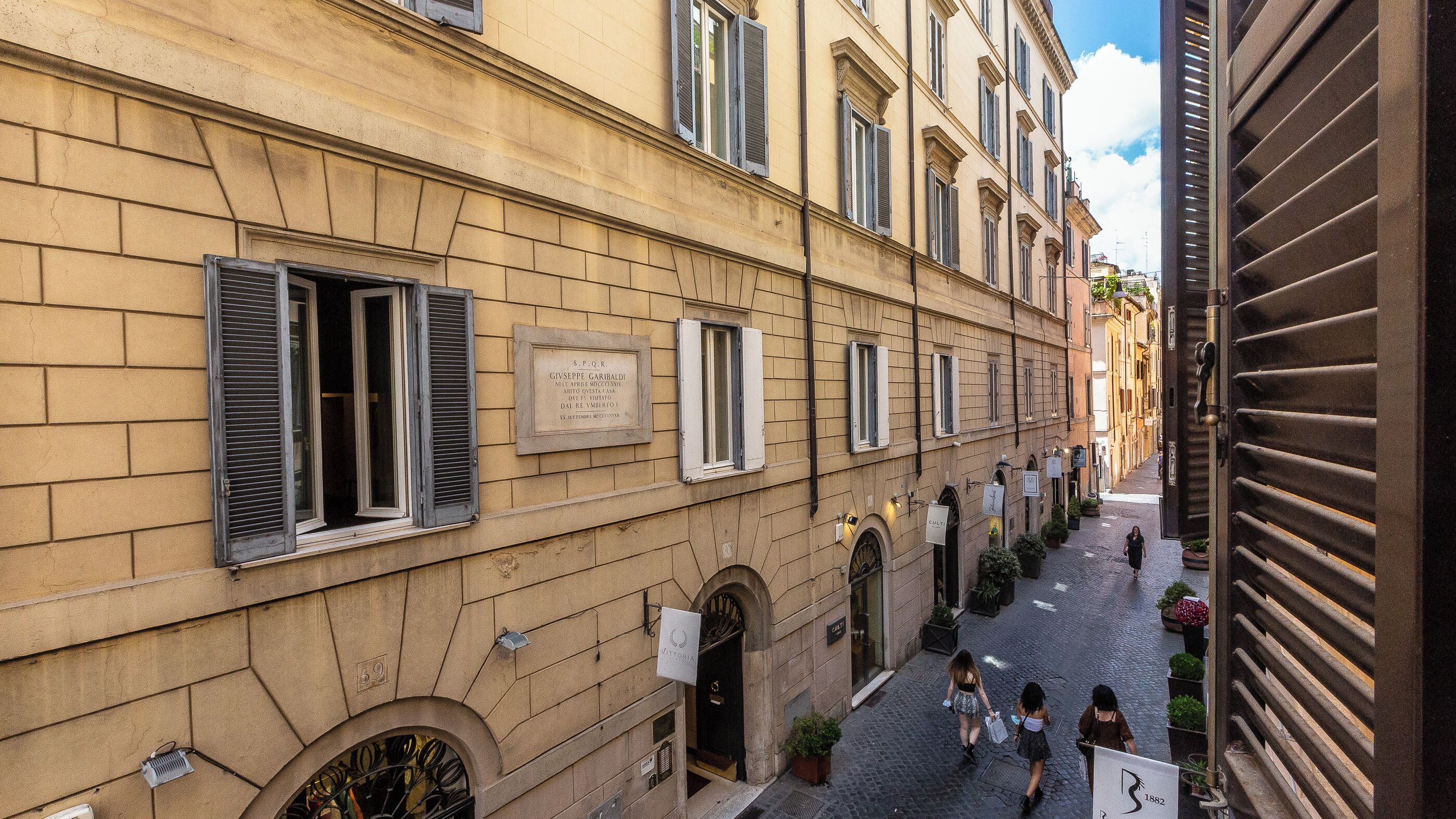 A narrow street with historic buildings, a sign indicating a restaurant, and a few pedestrians.