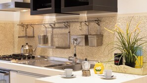A modern kitchen with stainless steel appliances, a sink, and a countertop with a coffee maker, teapot, and cups. - Rental in Rome Vittoria Apartment (Rome)