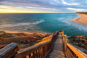 A wooden boardwalk leading to a beach with ocean views. - Reef Retreat Modern Beach HouseSanctuary (Port Noarlunga)